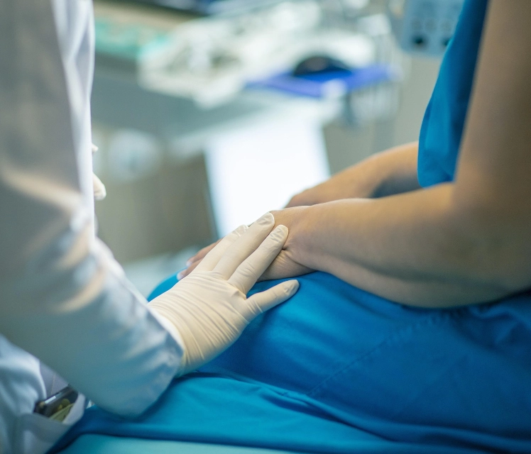 Main posée sur celle d’un patient en blouse bleue, illustrant un accompagnement thérapeutique bienveillant à l’hôpital dans le Lot (46)