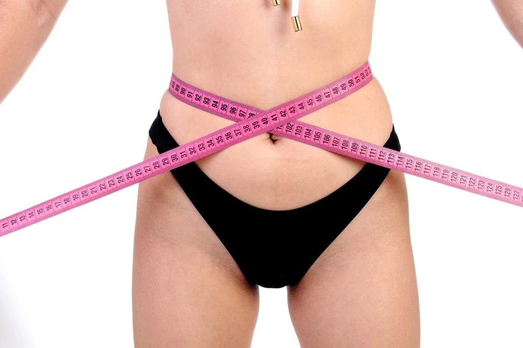 Femme qui mesure son tour de taille., espère trouver sa silhouette idéale. C'est possible ; l'hypnose et PNL pour maigrir durablement - proche de Cahors